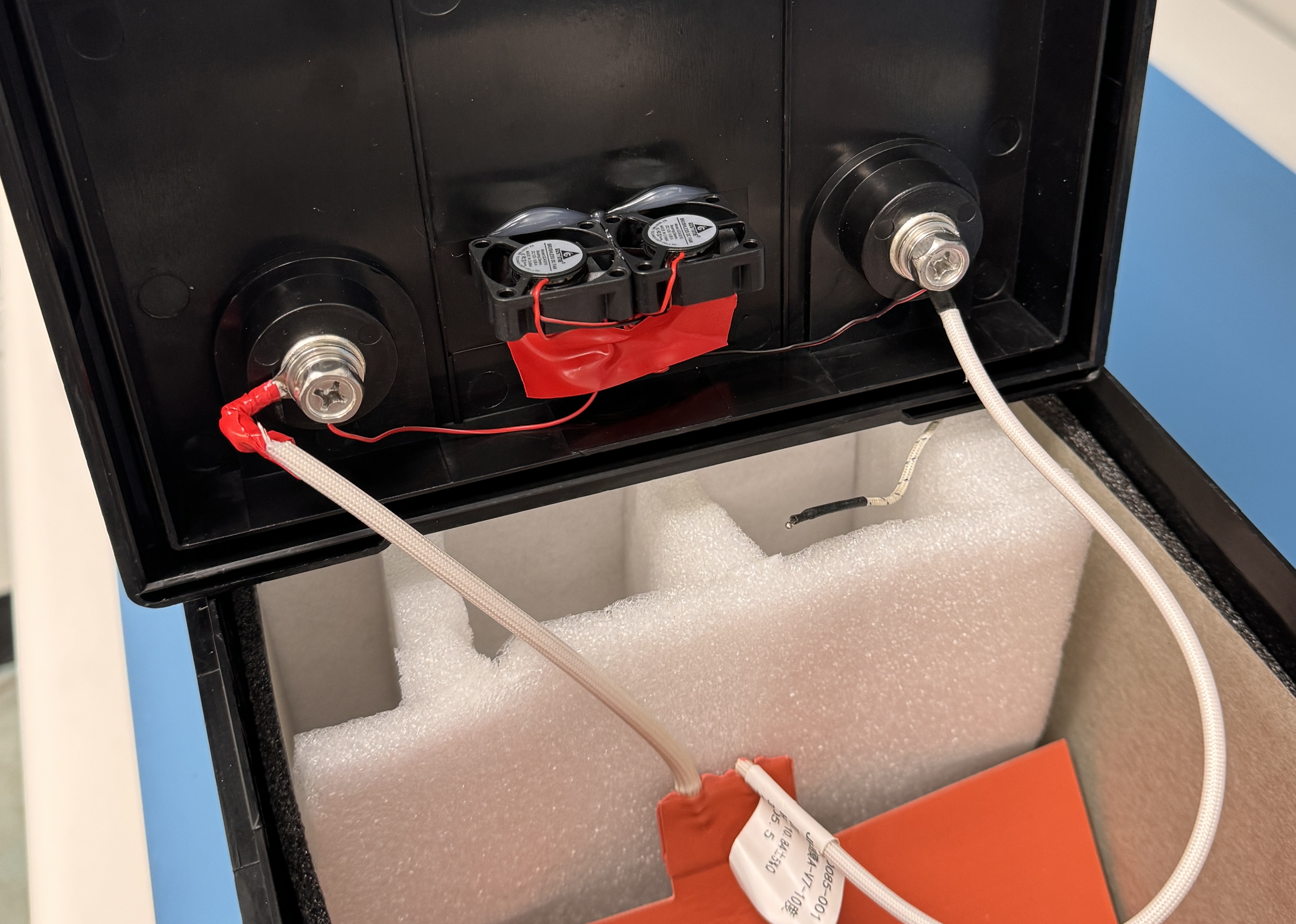 Interior of the battery test chamber showing insulation, heating pad, and thermistor lead